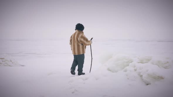 Wide Shot Winter Landscape with Indigenous Senior Man Walking with Stick in Slow Motion