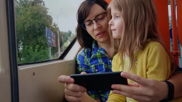 Mother and Daughter Together Use Smartphones and Ride in the Tram