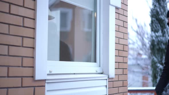 Window with Masked Man Approaching Looking Inside Empty House