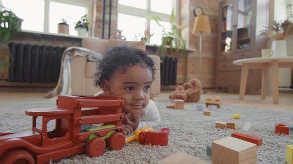 Close Up of Adorable Toddler on Floor with his Toys