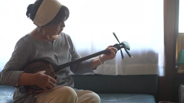 A woman practicing playing the sanshin