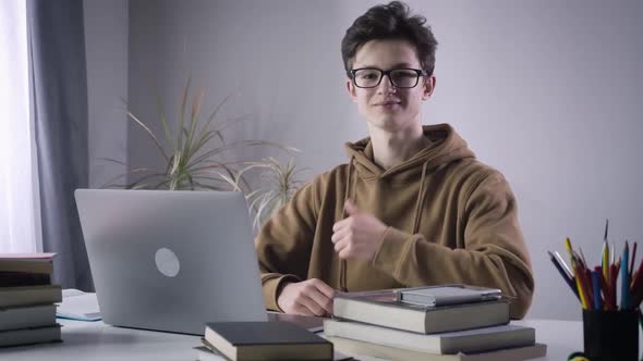 Smart Caucasian Boy Showing Thumb Up and Smiling at Camera. Portrait of Intelligent Male College