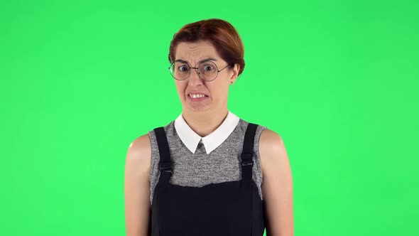 Portrait of Funny Girl in Round Glasses Is Showing Disgust for Bad Smell or Taste. Green Screen