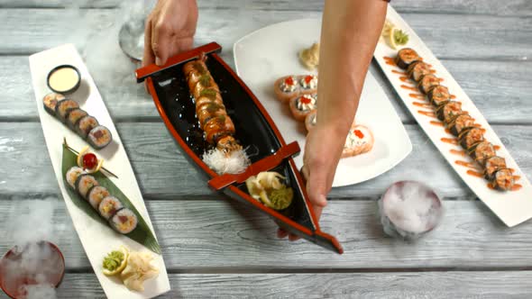 Hands Holding Plates with Sushi.
