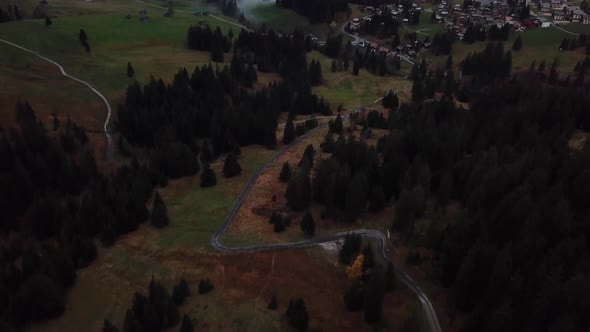 Aerial Tilt Up View From Path To Reveal Houses In Arvenbuel Switzerland And Mist Covered Valley