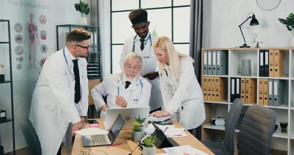 Team of Doctors Working Together in Medical Workroom and Discussing Reports and Information