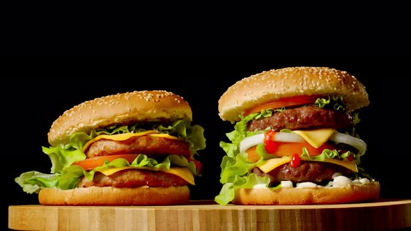 Two Craft Beef Burgers on Wooden Table Isolated on Dark Grayscale Background