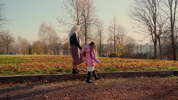 Mother and daughter walk at autumn forest park. Two females persons spend time together outdoors