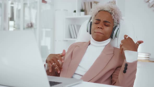 African American Woman in Headphones Listening to Music Imagine Playing Guitar