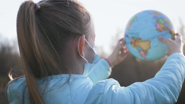 Sad Child Girl in Medical Mask Holding the Globe