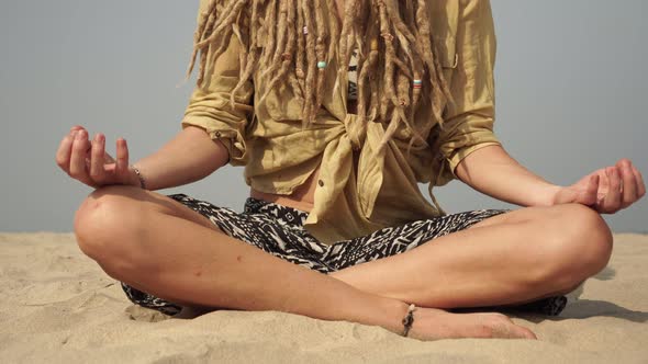 Hippie Woman Practices Yoga and Meditation in the Lotus Position on the Seaside