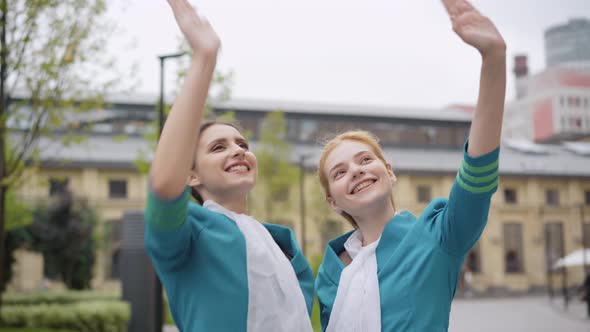 Positive Young Slim Women in Stewardess Uniform Waving and Looking Up. Portrait of Smiling Elegant