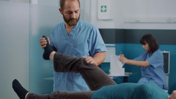 Male Therapist Doing Orthopedic Exercise to Stretch Leg Muscles