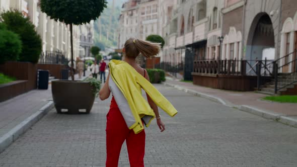 Happy Adult Woman Dressed in Bright Clothes is Walking on City Street in Summer