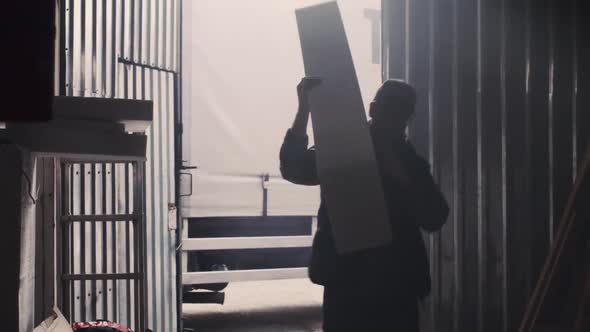 Man Carrying Plastic Block Into Hangar