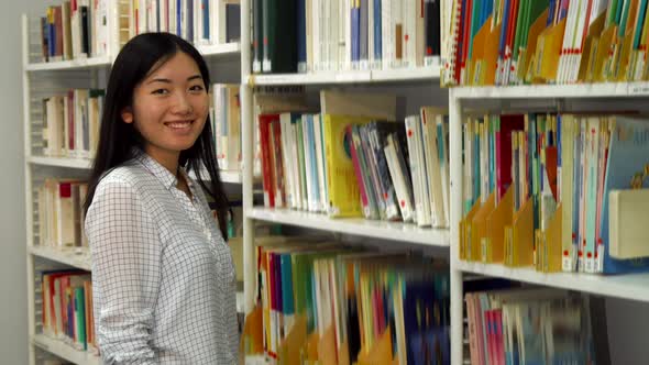 Girl Puts Academic Journals on the Rack at the Library