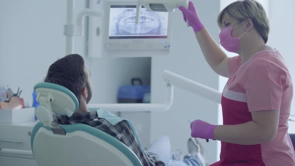 Dentist in Medical Mask and Gloves Checking the Mouth of the Patient Using Medical Tools