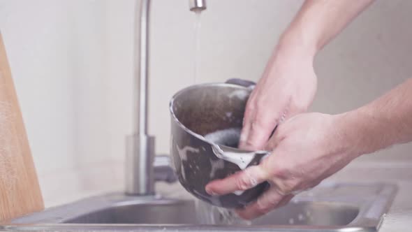 Hands Wash the Castiron Cauldron in the Sink and Rinse with Water From the Detergent