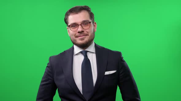 Portrait of an Elegant Cheerful Man Standing on a Green Background and Looking Into the Camera