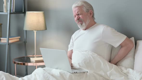 Old Man with Laptop Having Back Pain in Bed 