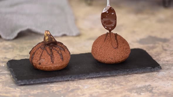 French Dessert Chocolate Choux Au Craquelin. Pouring Chocolate Over the Profiteroles.