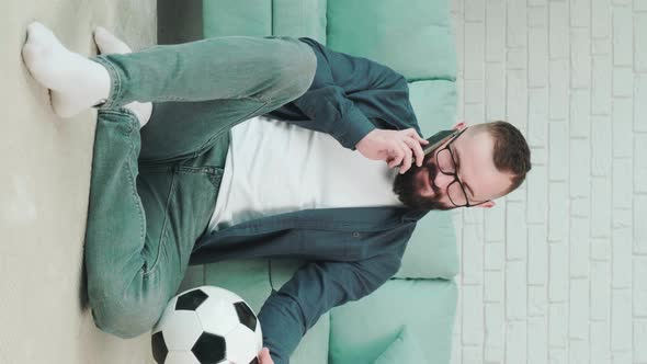 Man Standing with Soccer Ball in Hands and Talking on the Phone