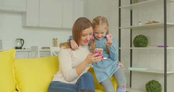 Mother and Cute Girl Browsing Online on Cellphone