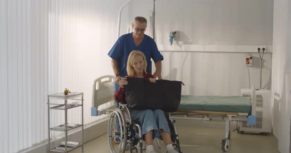 Male Orderly Pushing Senior Female Patient Being Discharged From Hospital in Wheelchair