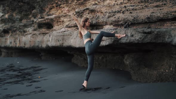 Woman Doing Stretching Exercises on Black Sand Beach Near Cliff Slow Motion