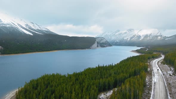 Aerial footage of the majestic nature with snow-capped mountains, immense lake and spring forest