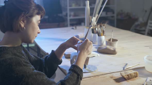 Woman creating ceramic cup from clay.