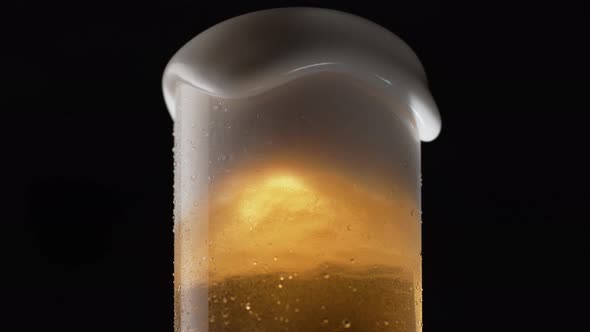 Close-up beer in glass. Foam overflowing. Slow Motion.