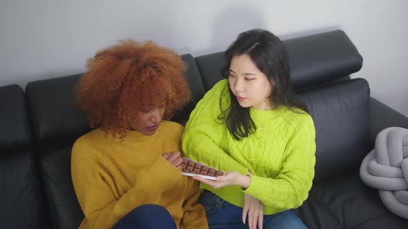 Young Asian Woman Offering Cocolate To Her Sad Arican American Black Friend. Support During Hard