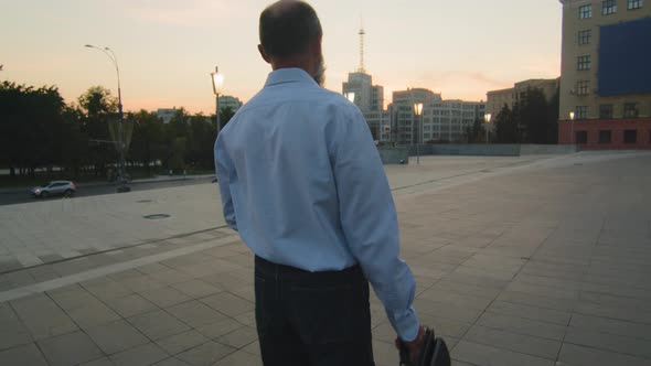 Back View of Elderly Tired Caucasian Man in White Shirt with Business Briefcase Returning in Evening