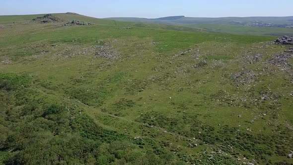 Wide shot aerial tracking forward over the wide expanse of Dartmoor, tors, grassy moorland and rocky