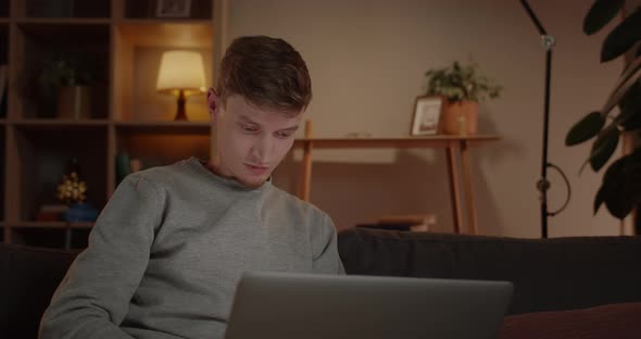 Crop View of Young Man Freelancer Using Laptop While Sitting on Couch at Home