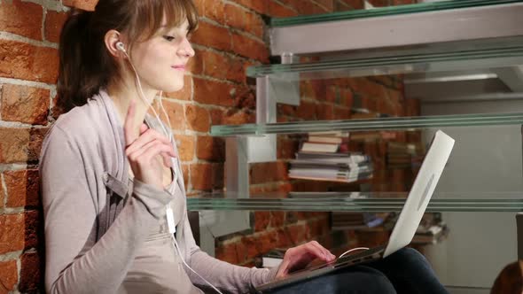 Woman Listening Music on Laptop and Dancing Sitting on Stairs