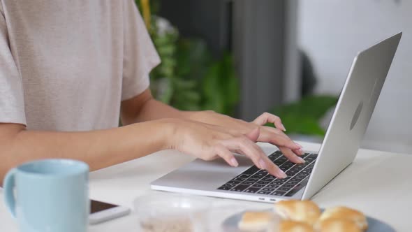 Close Up Asian woman working at home and typing keyboard using a laptop.