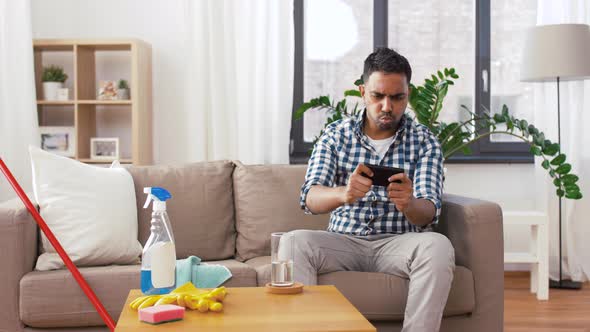 Man Playing Game on Smartphone After Cleaning Home 24