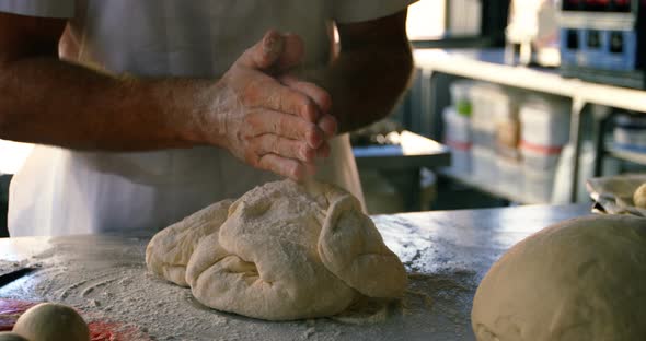 Chef kneading dough on worktop in kitchen 