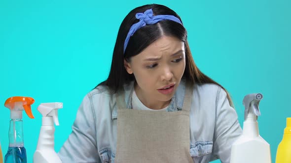 Inexperienced Housewife Looking at Detergents Assortment and Holding Head