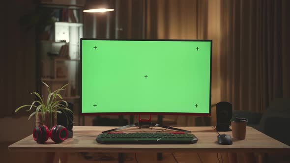 Desk With Mock Up Green Screen On Personal Computer With Big Display At Night