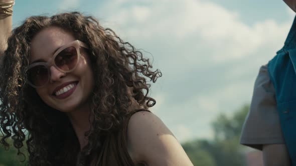 Camera tracking smiling young caucasian woman with curly hair dancing at music festival among friend