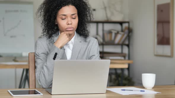 Pensive African Businesswoman Thinking and Working on Laptop