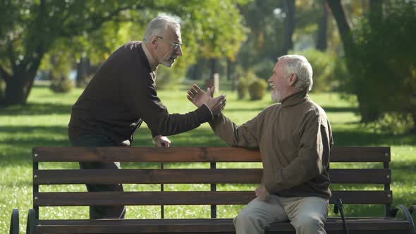 Elderly Man Starting Arm Wrestling Competition in Park, One Man Cheating to Win