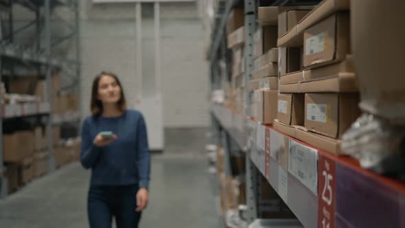 Woman with a Phone Looking for a Product in a Warehouse Store