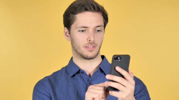 Man Using Smartphone on Yellow Background