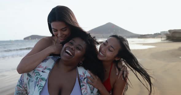 Happy multiracial women walking on the beach - Young people enjoy summer vacation together