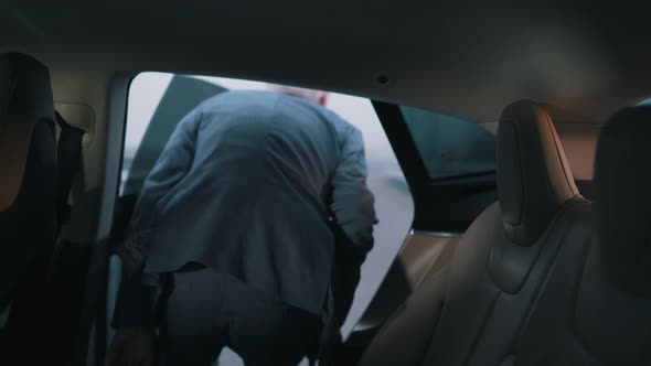 an Elderly Businessman Leaves the Back of a Car