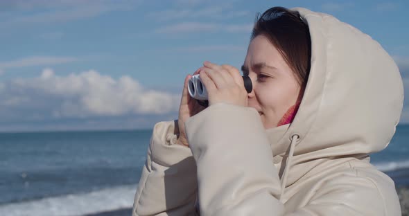Young Smiling Female Looking Through Binoculars at Something Interesting in Sea